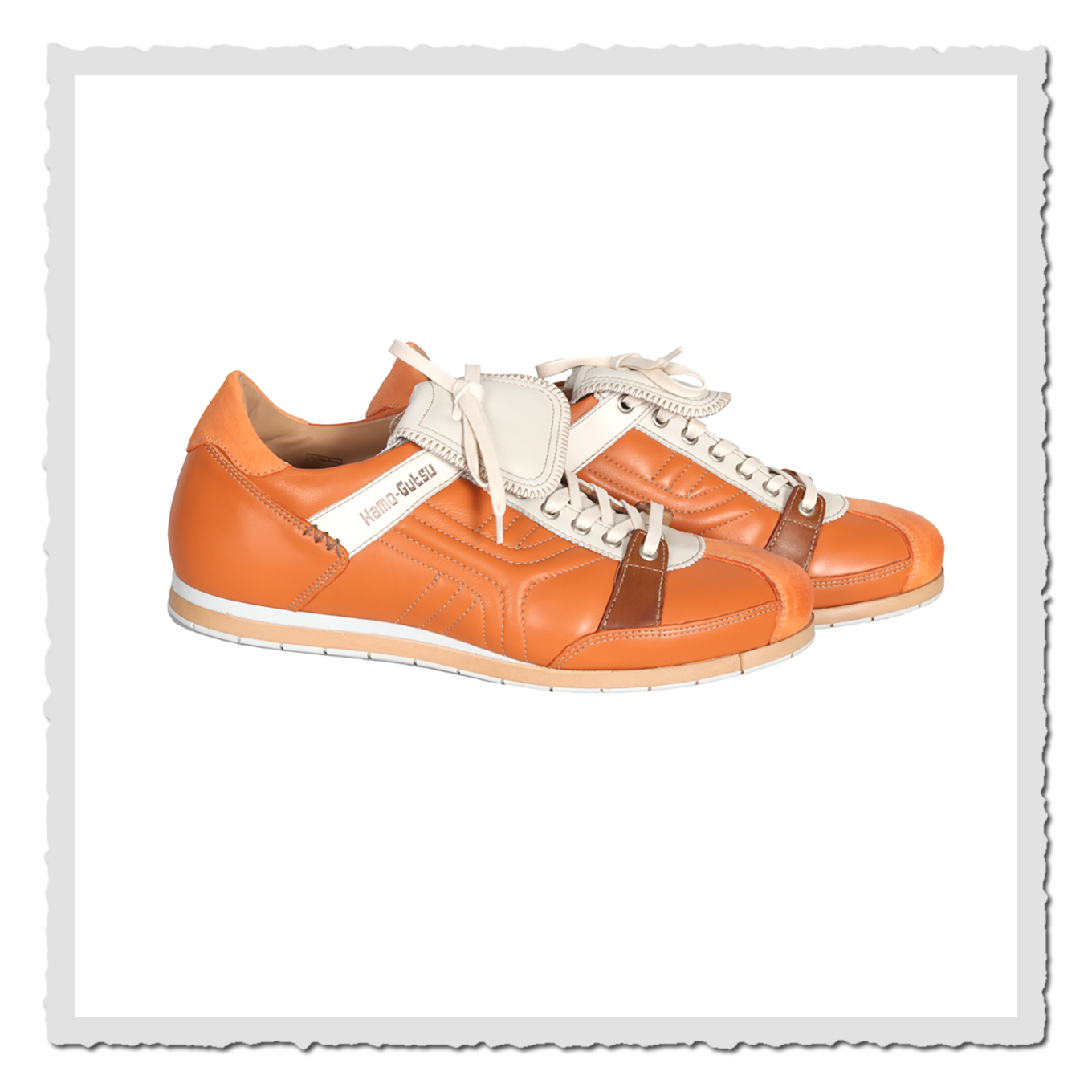 Zwei orange Freizeitschuhe in Seitenansicht vor weissem Hintergrund, mit heller Schnürung und braunen Details.